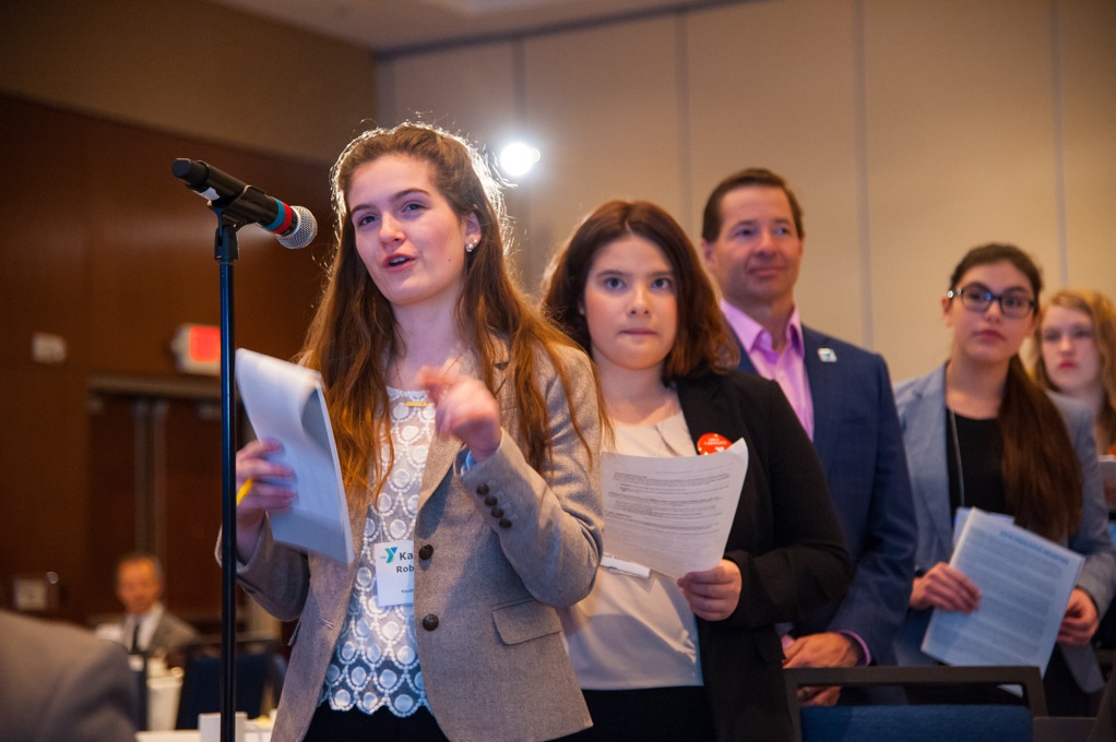 Young professionals lined up behind a microphone holding papers