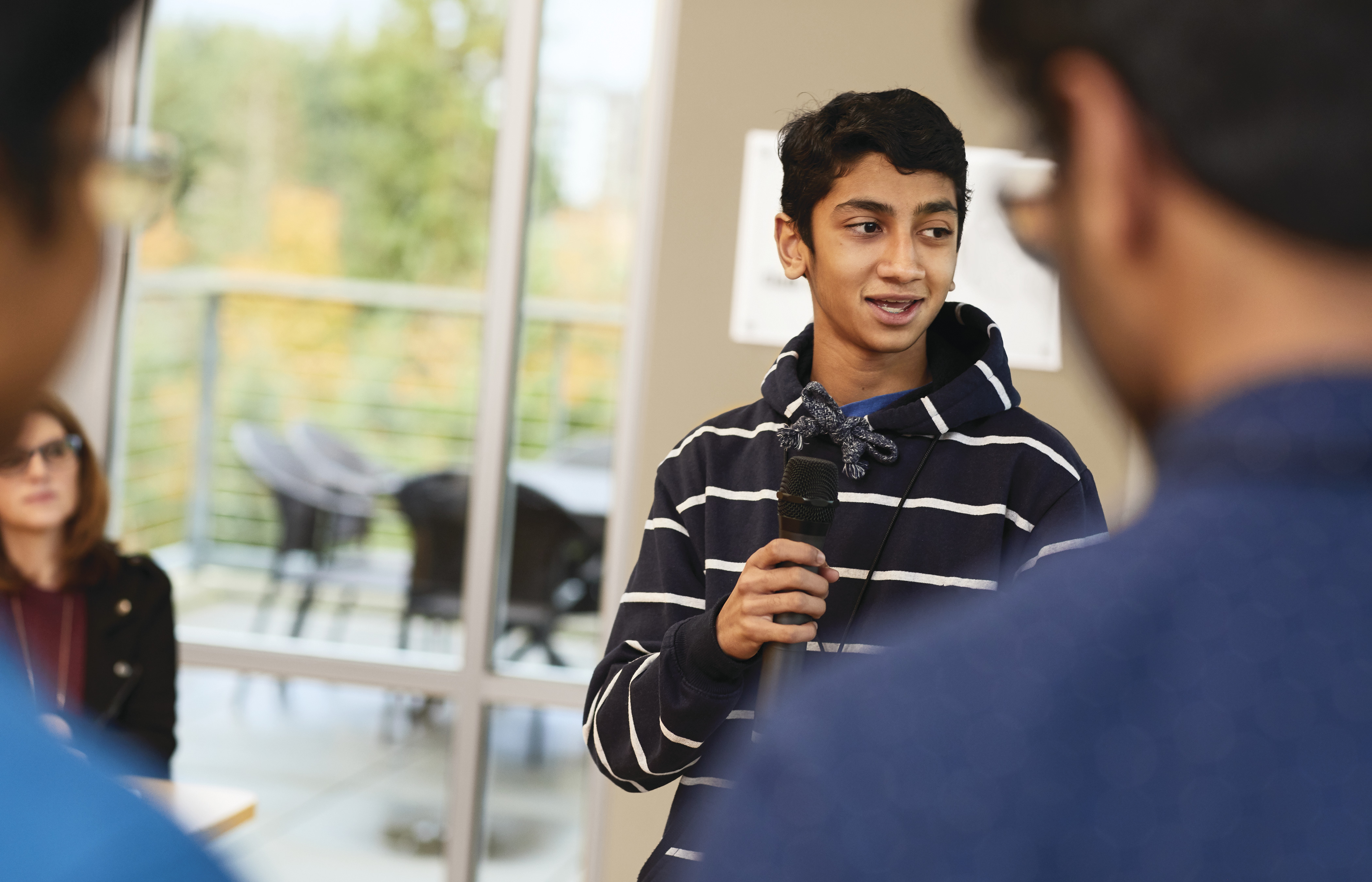 Teen in a hoodie speaking in a microphone
