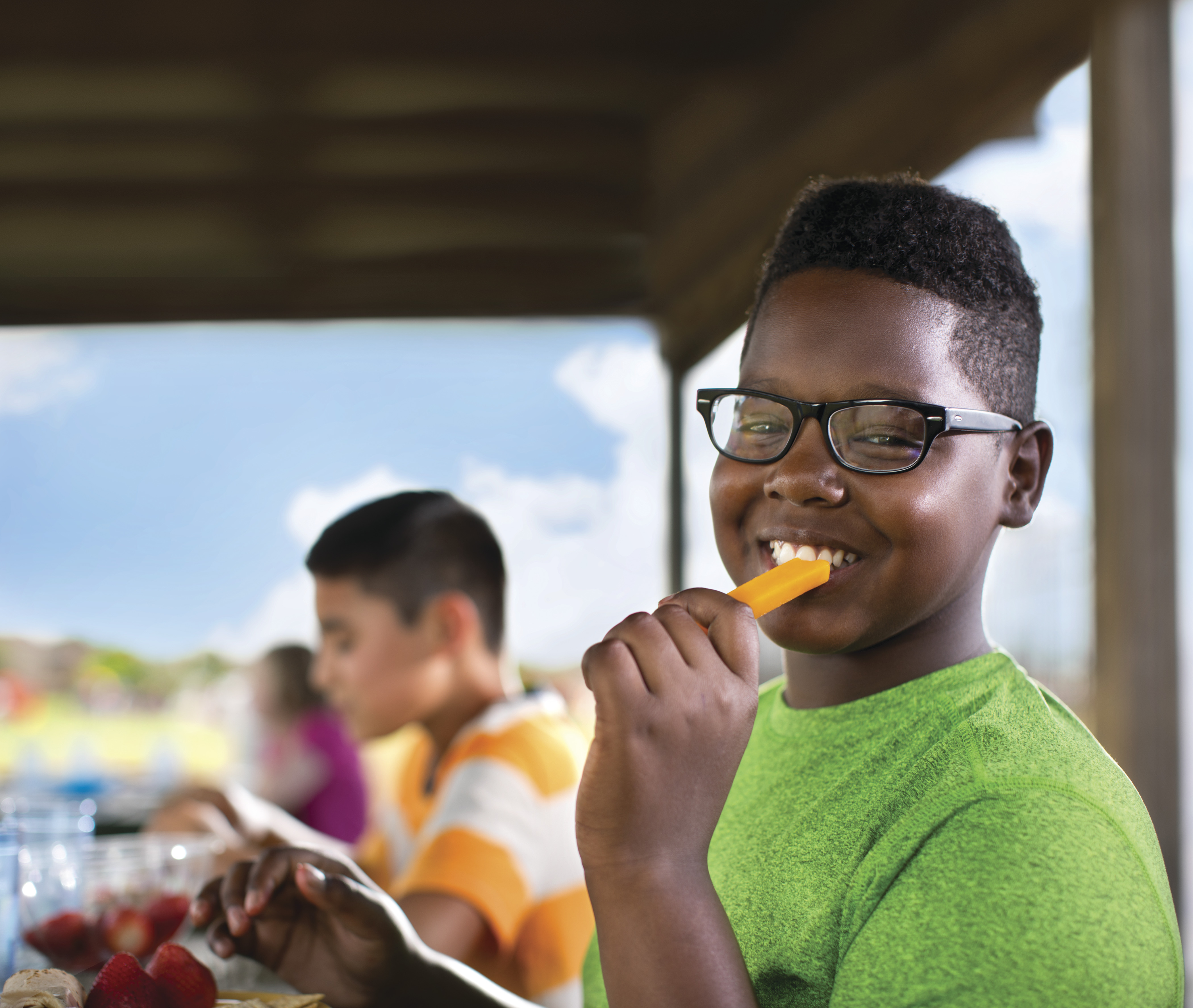 Smiling child eating a cheese stick