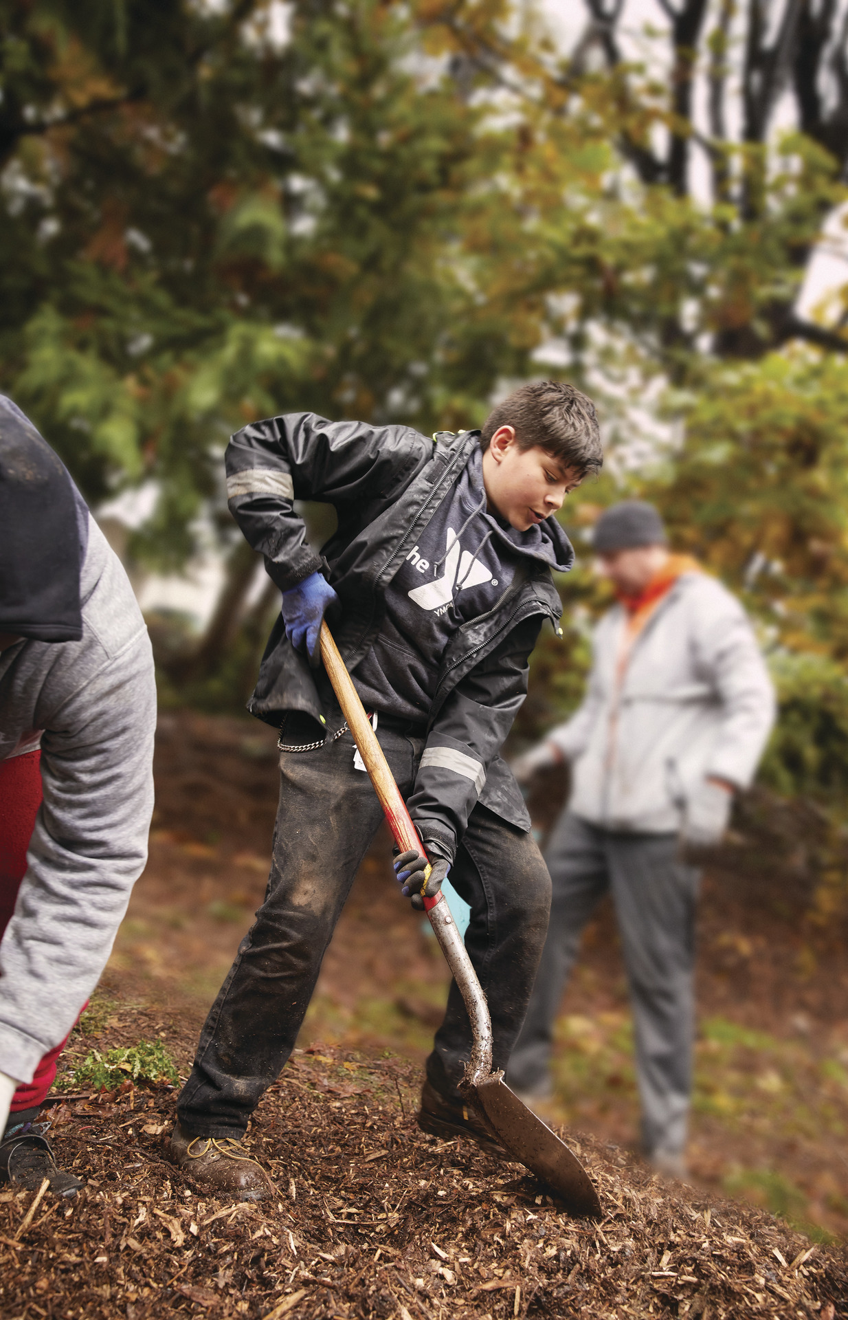 YMCA youth volunteers outside shoveling mulch