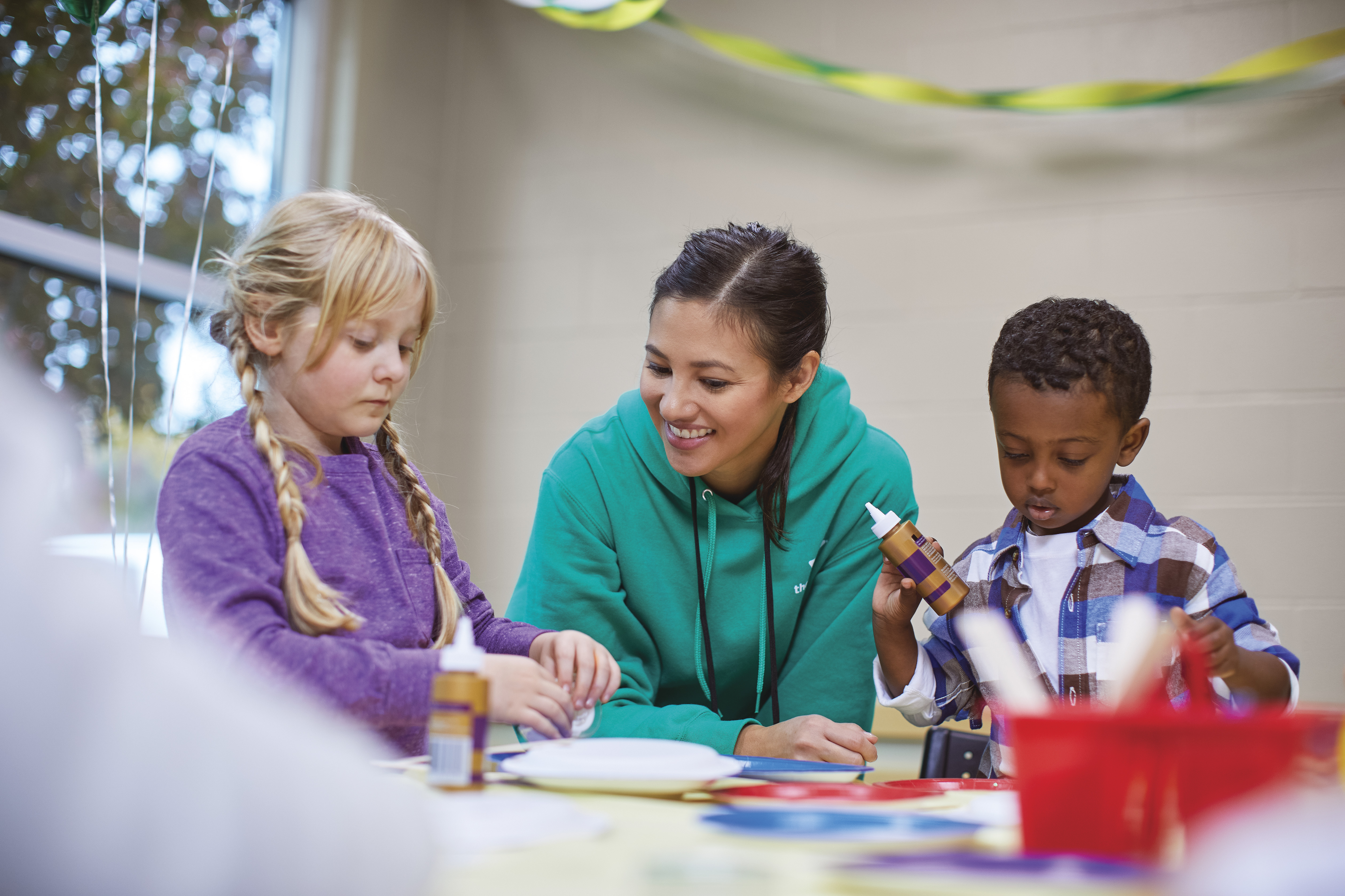 YMCA faculty helping kids craft during a birthday party