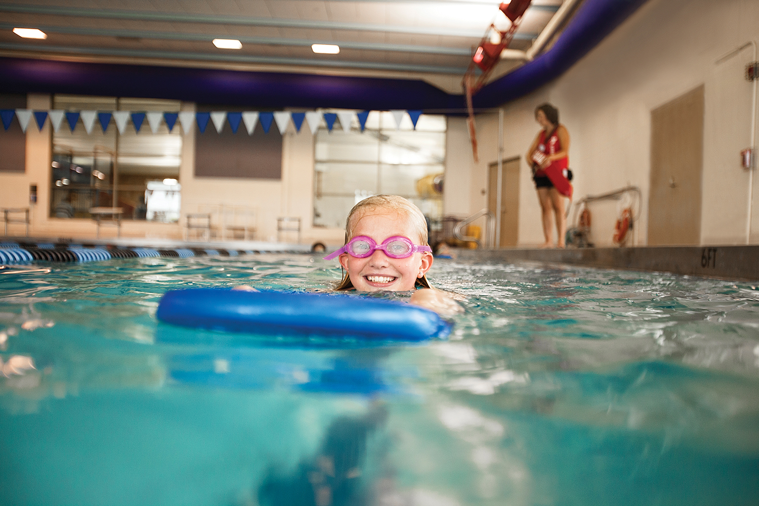 Young girl in pool with kick board 
