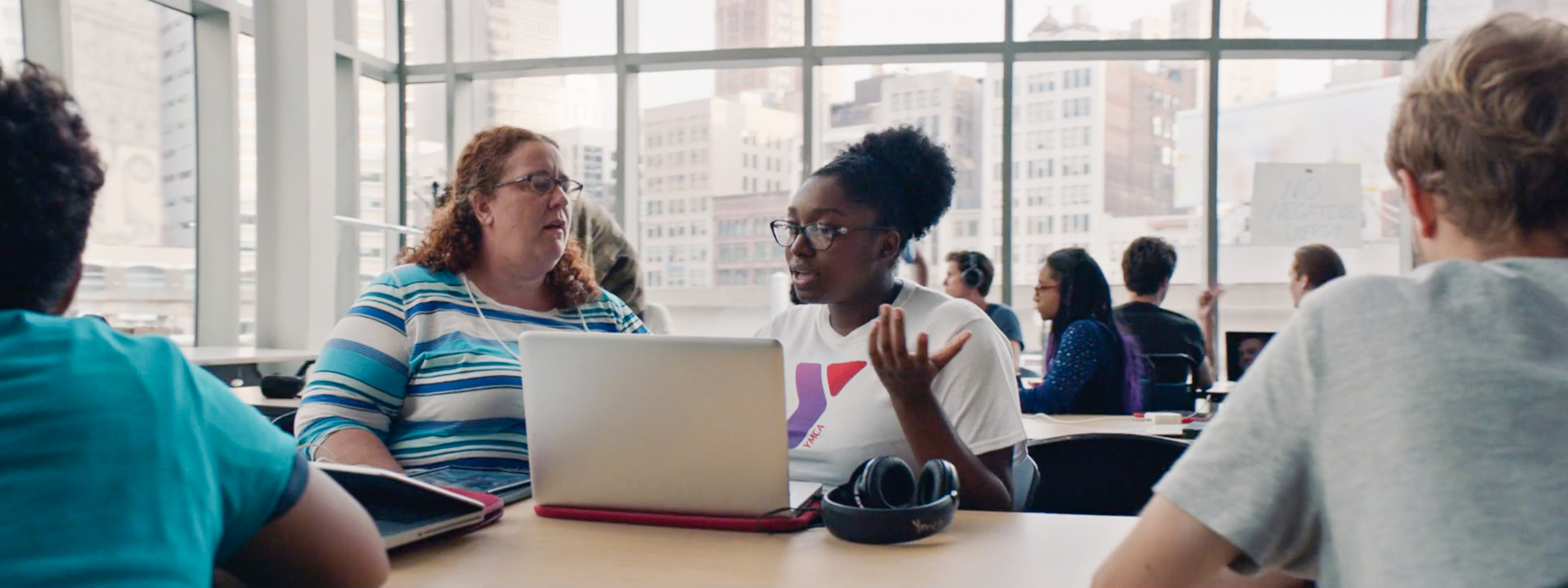 YMCA student working at computer with help from staff