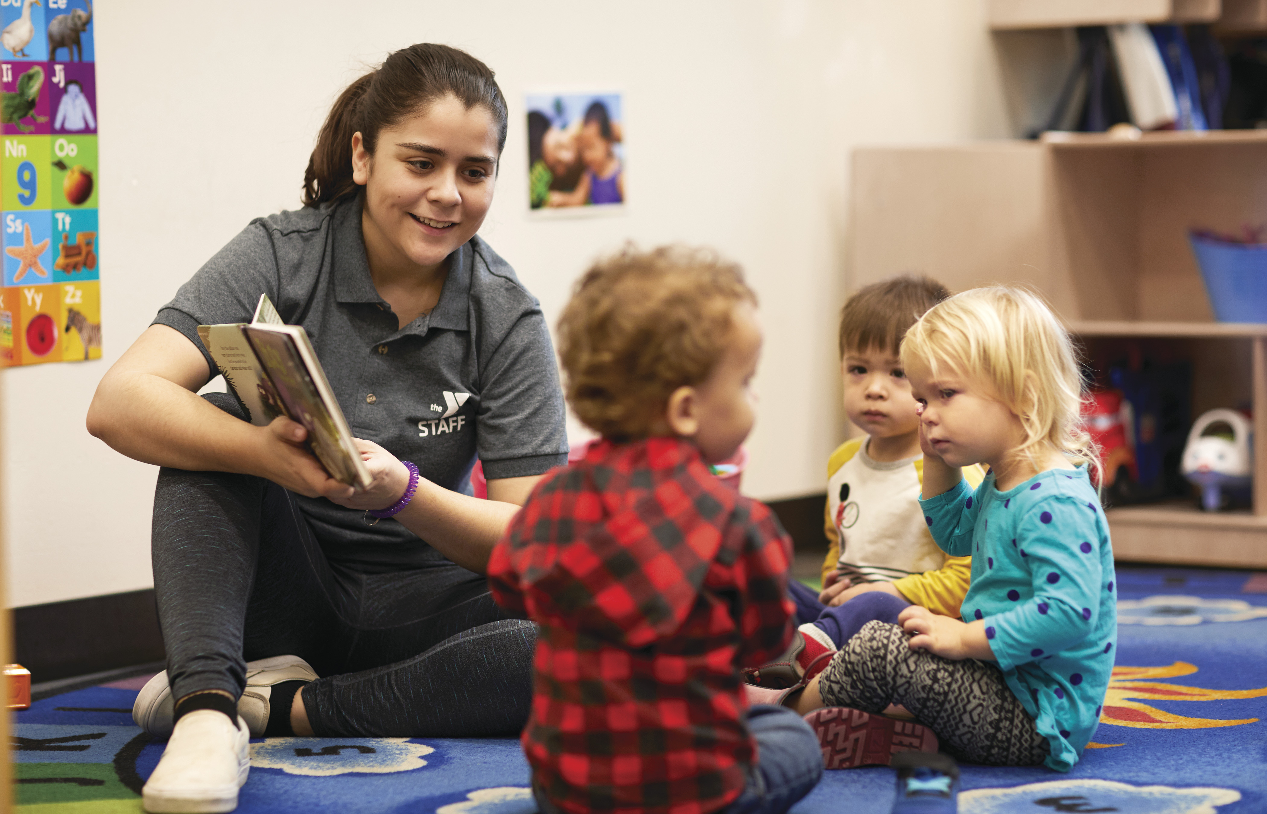 Child Care Learning Programs: YMCA daycare worker reading to toddlers 
