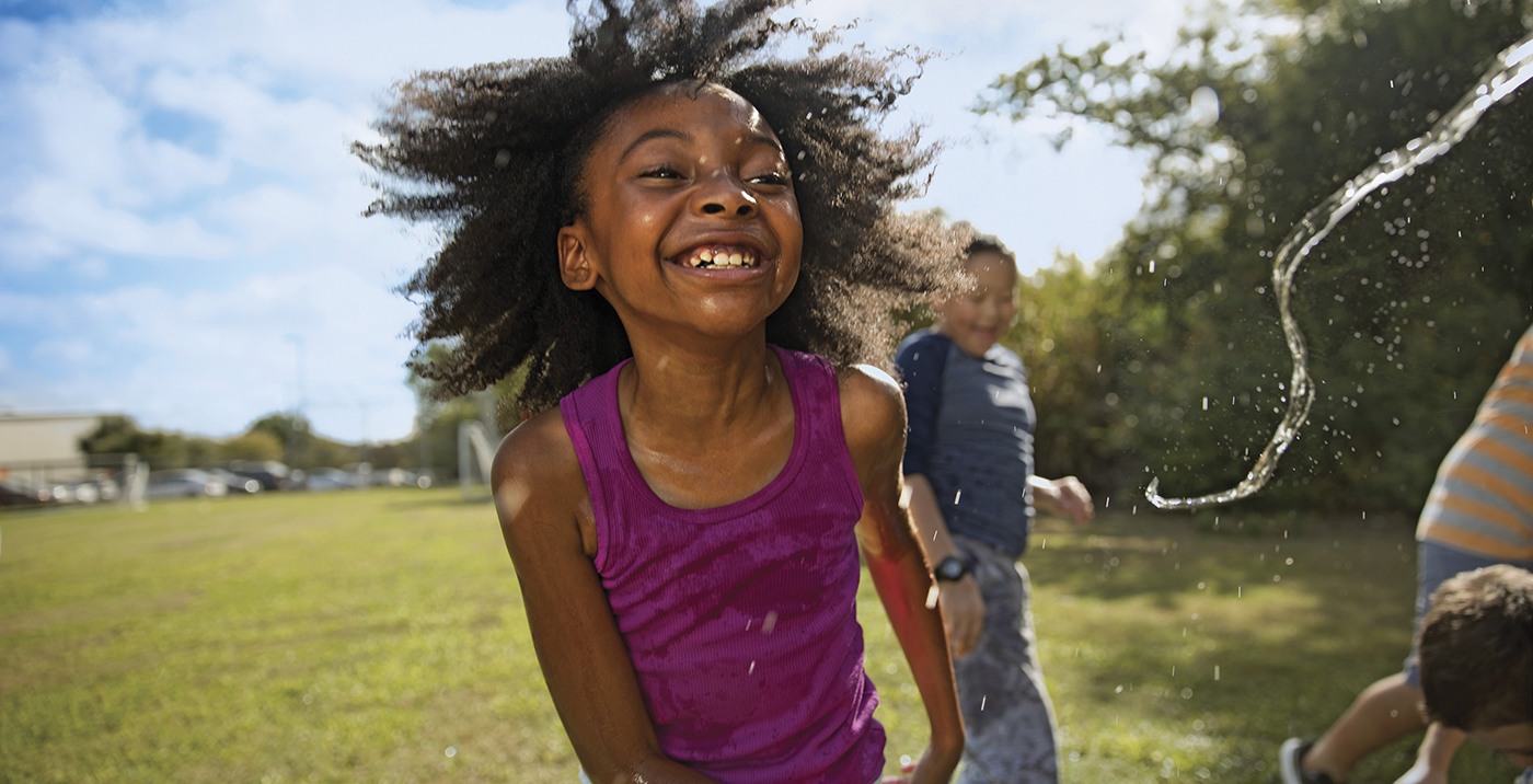 Young girl playing outside in water