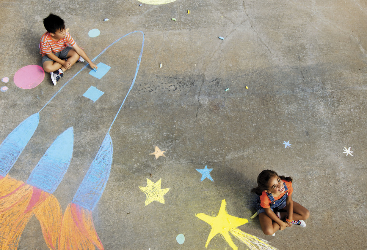 Children playing with chalk on sidewalk