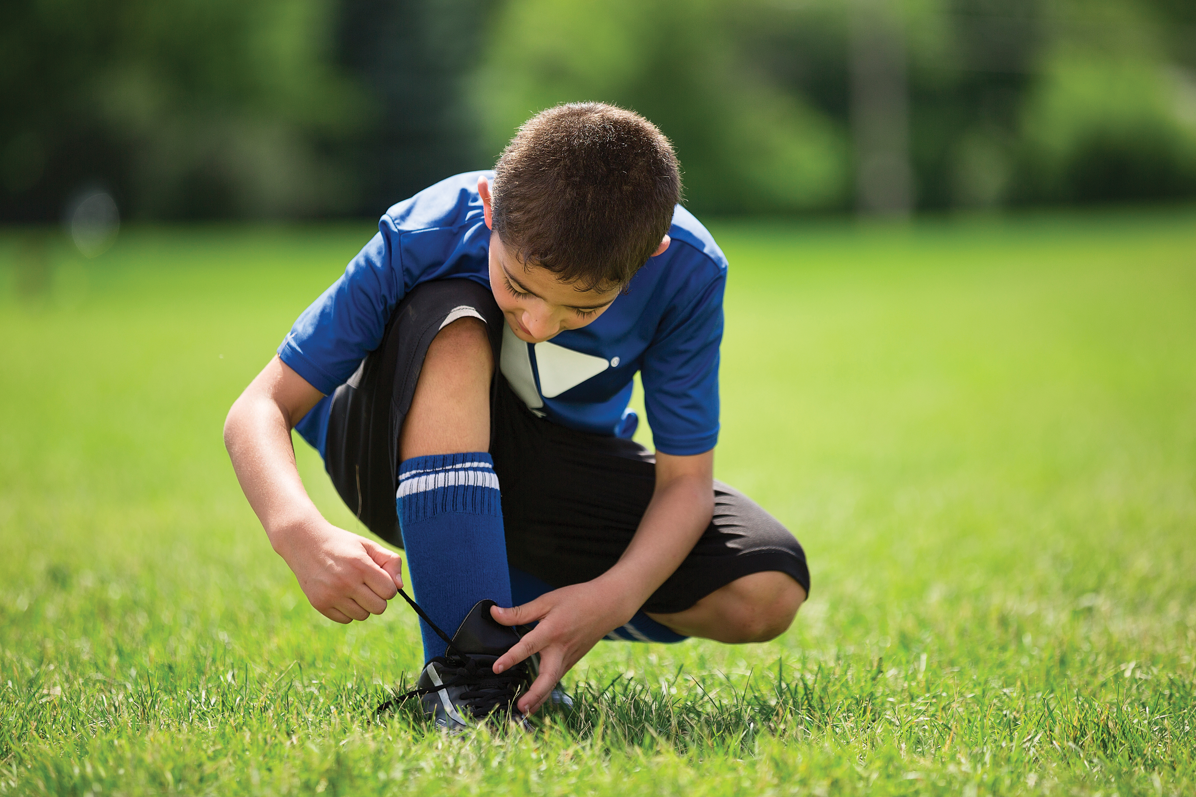 Youth in field tying  shoe