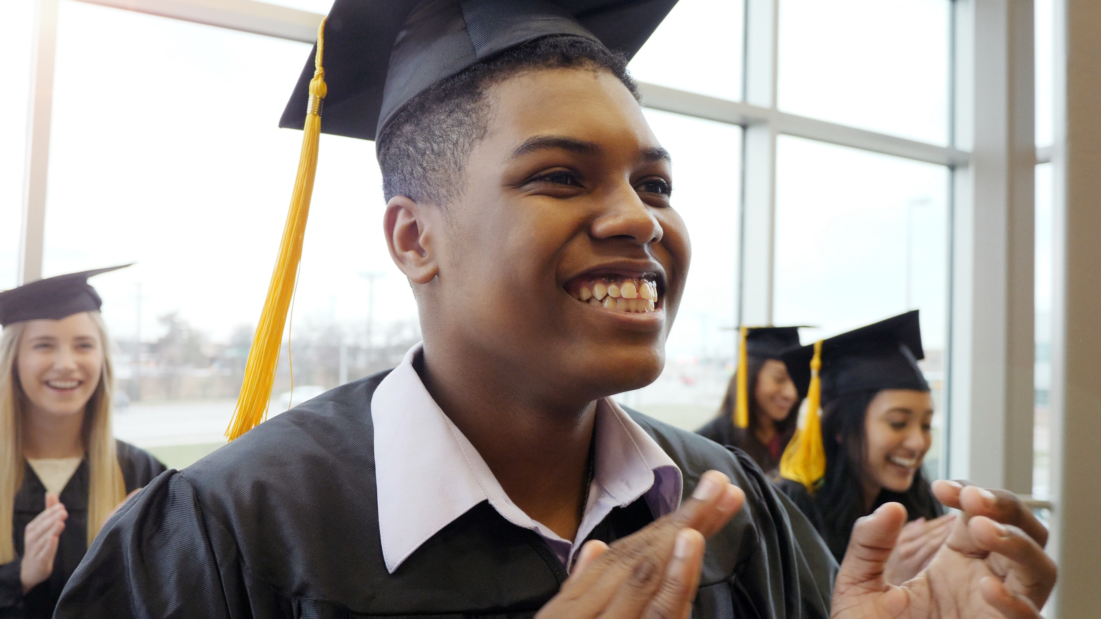 African American male smiling wearing graduation cap and gown