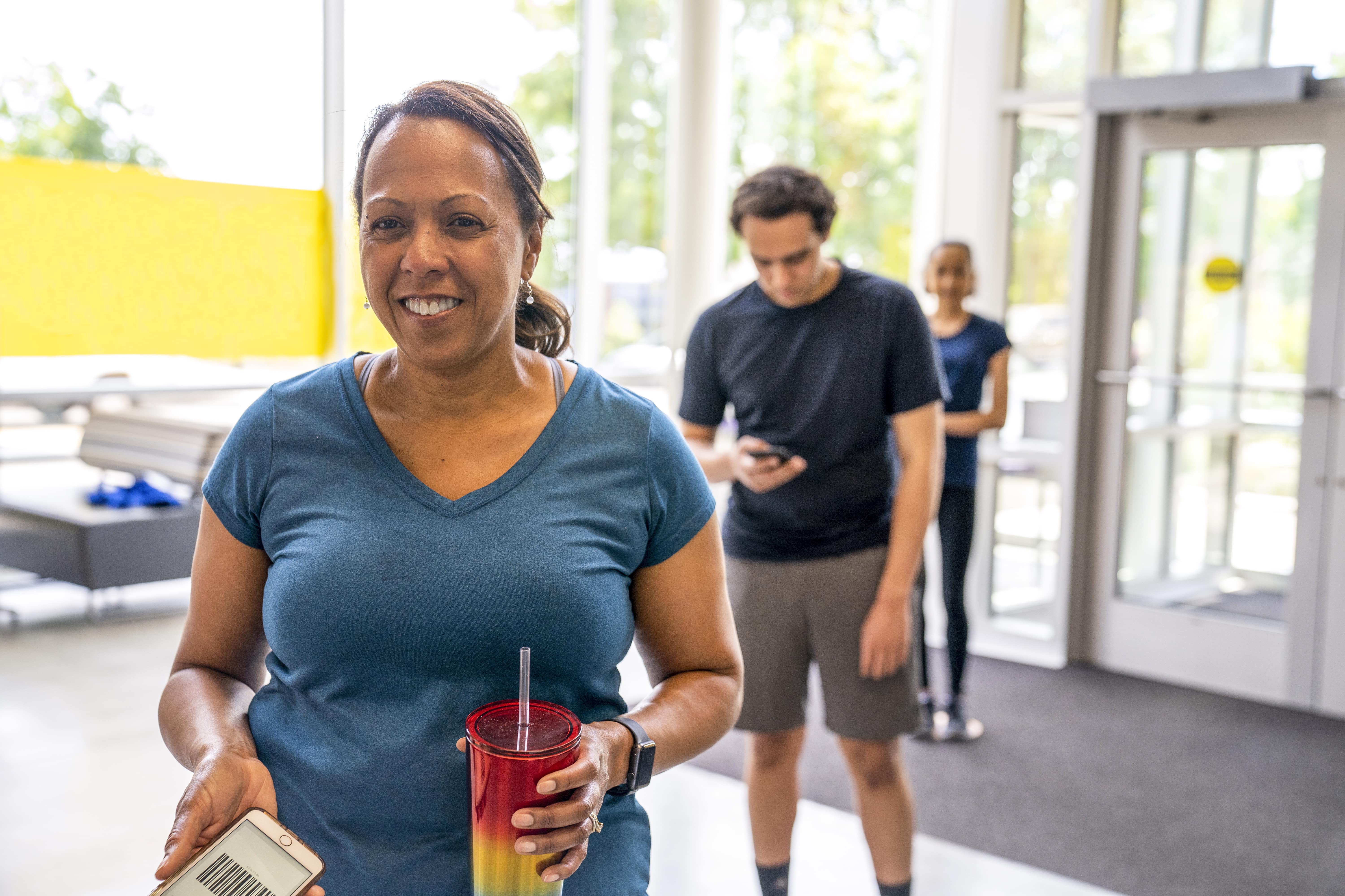 Woman holding plastic drink cup in line