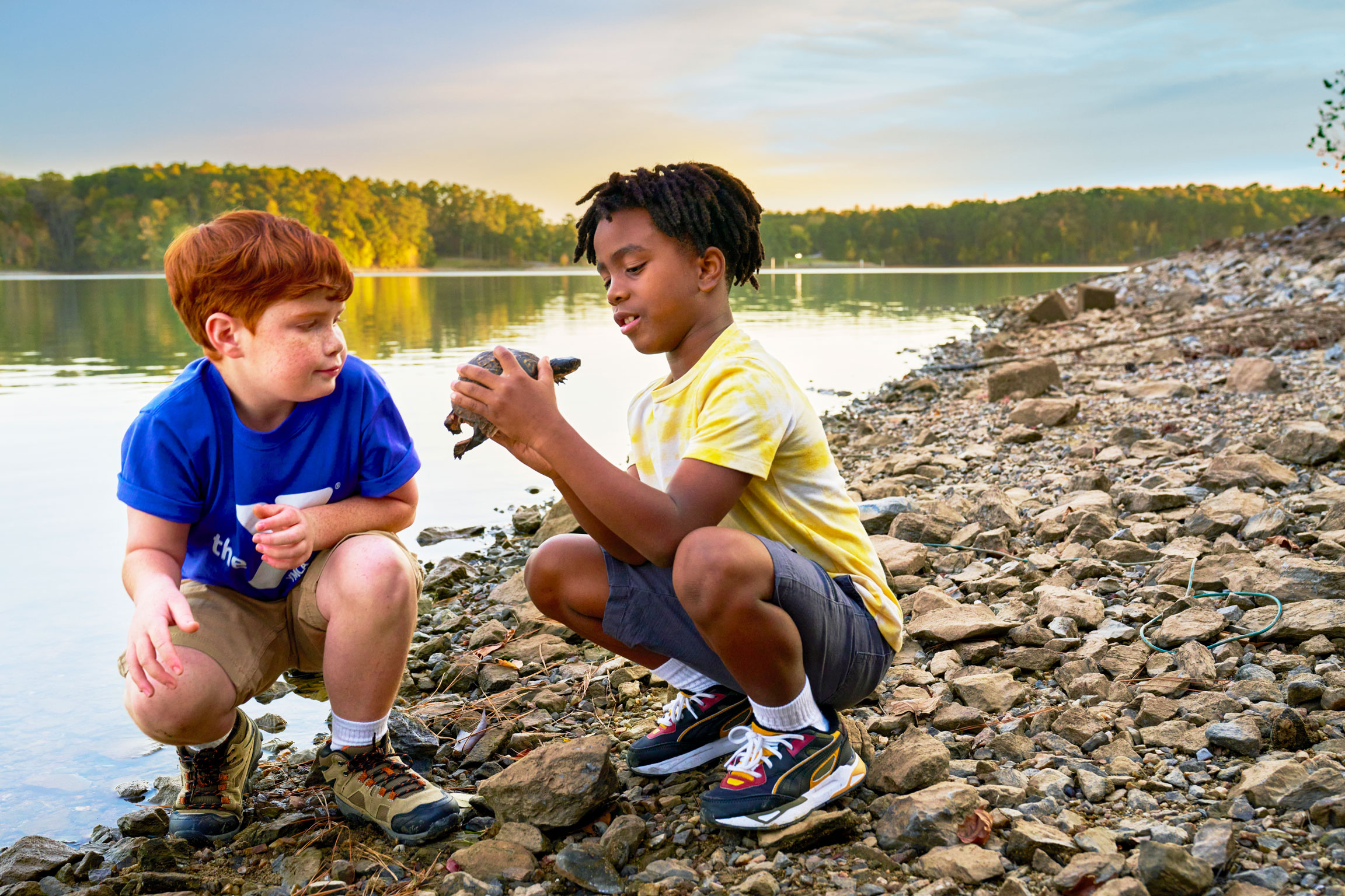 Two boys observing turtle by the lake at Y camp