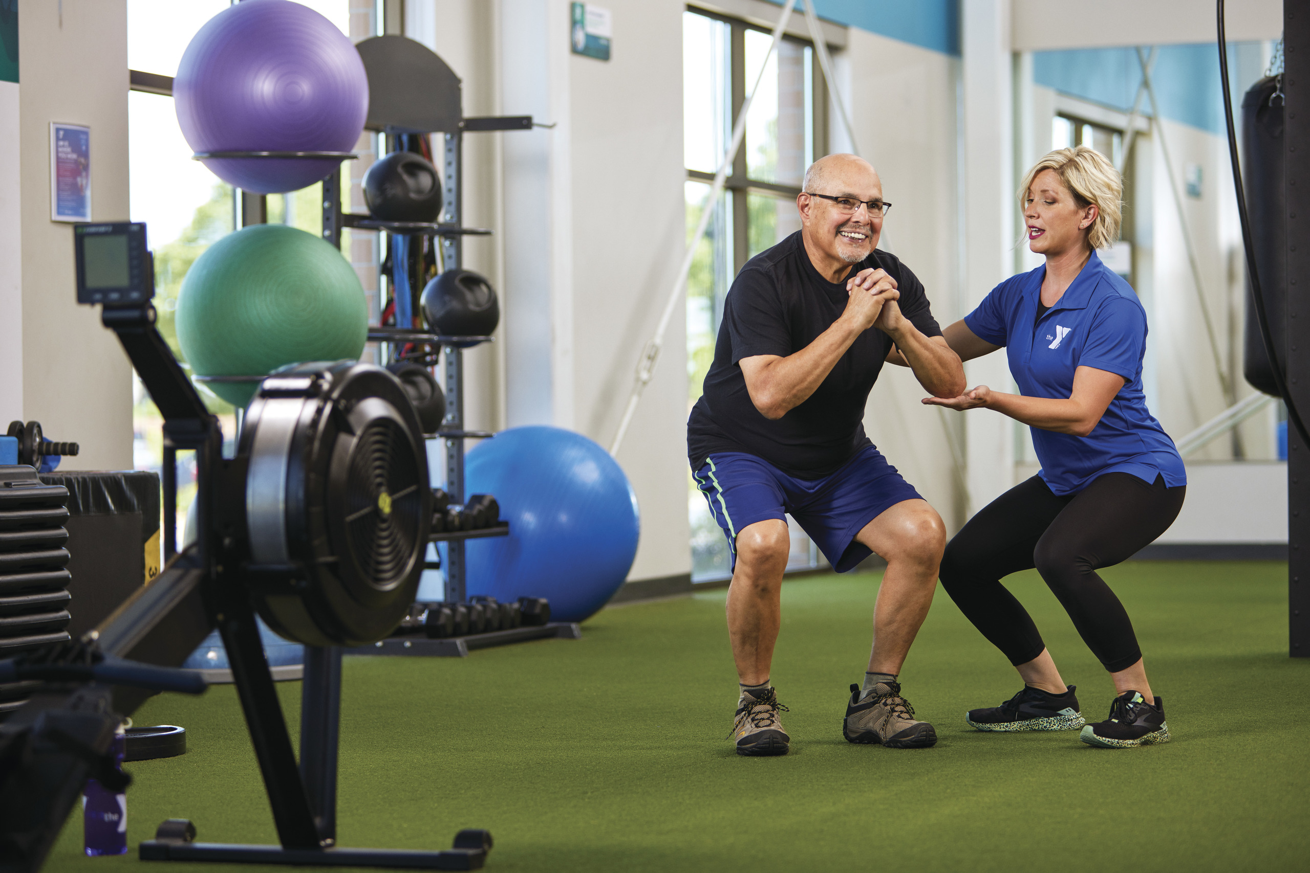 A personal trainer spotting a senior member at a YMCA gym