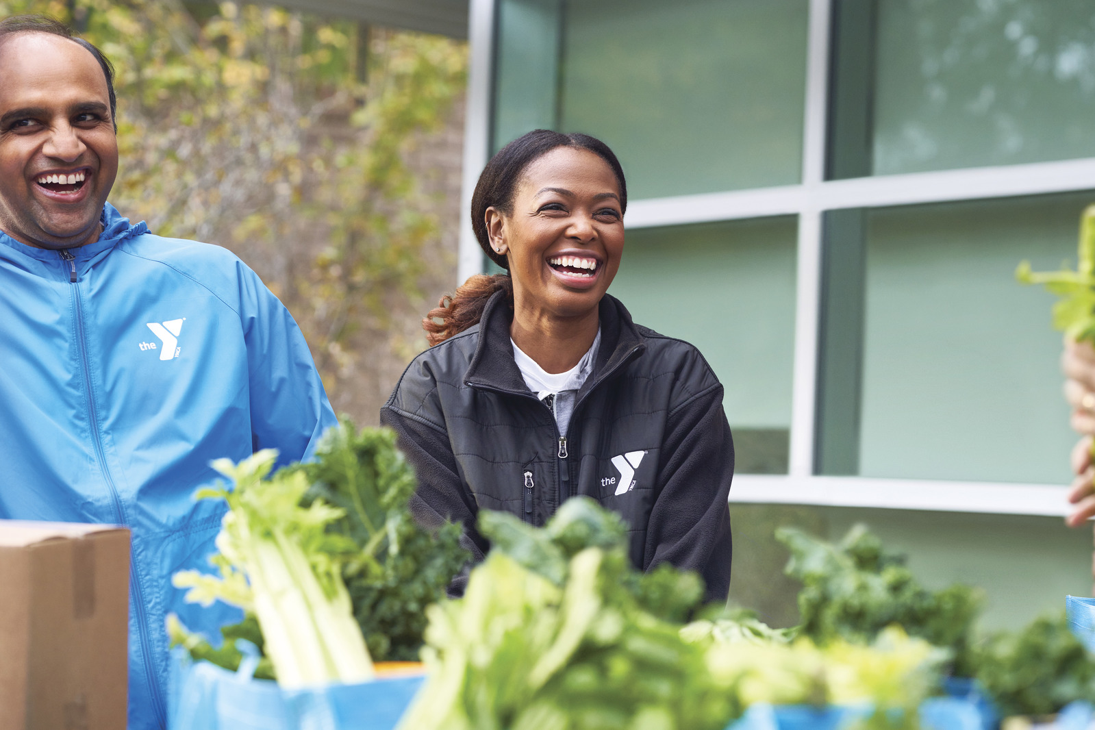 Two Y volunteers bagging vegetables and laughing