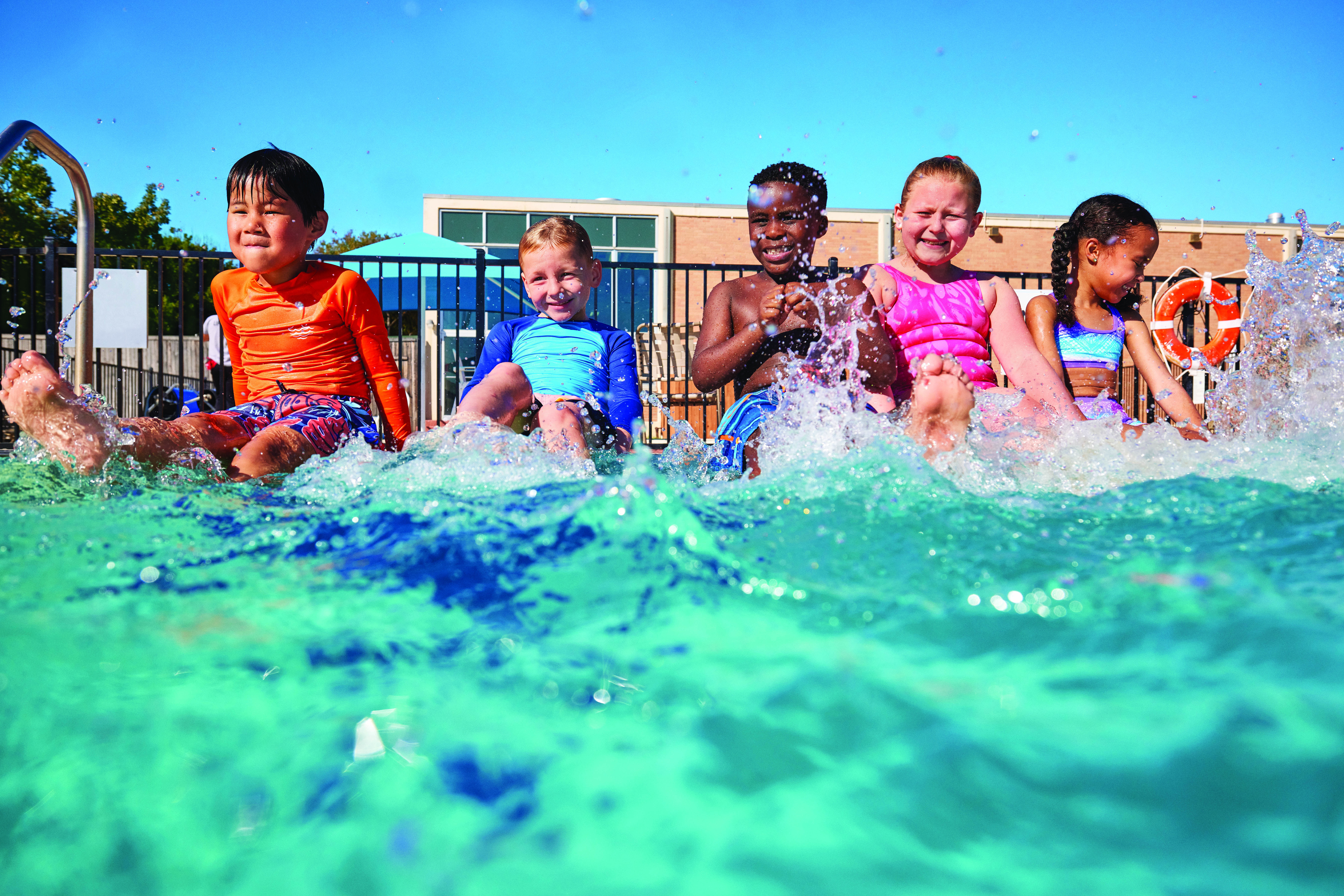 Kids sitting by edge of pool kicking their feet