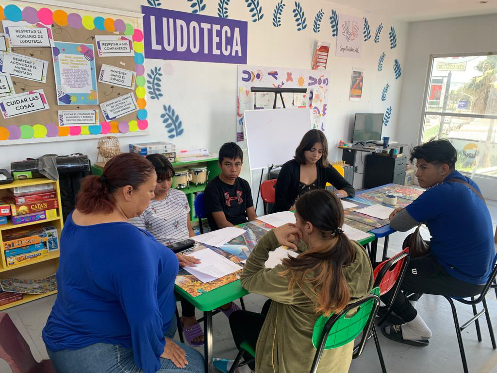Teens and adult working at table.