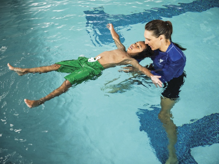 Instructor teaching child to swim - YMCA