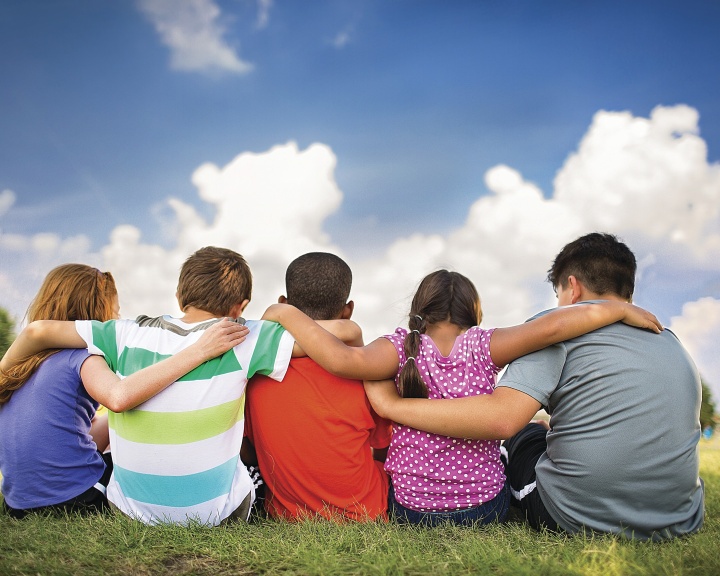Kids sitting on the grass with arms around each other
