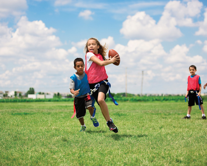 young girl running with football
