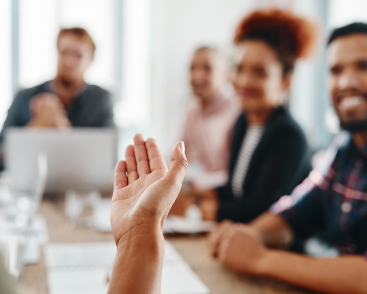 Group of people in board room looking at person holding hand out