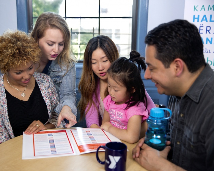 Group of people sitting around table looking at YMCA brochure